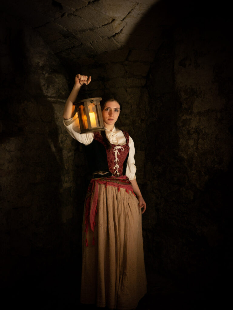 A women holding a lantern in the surrounds of the OXford Castle Crypt