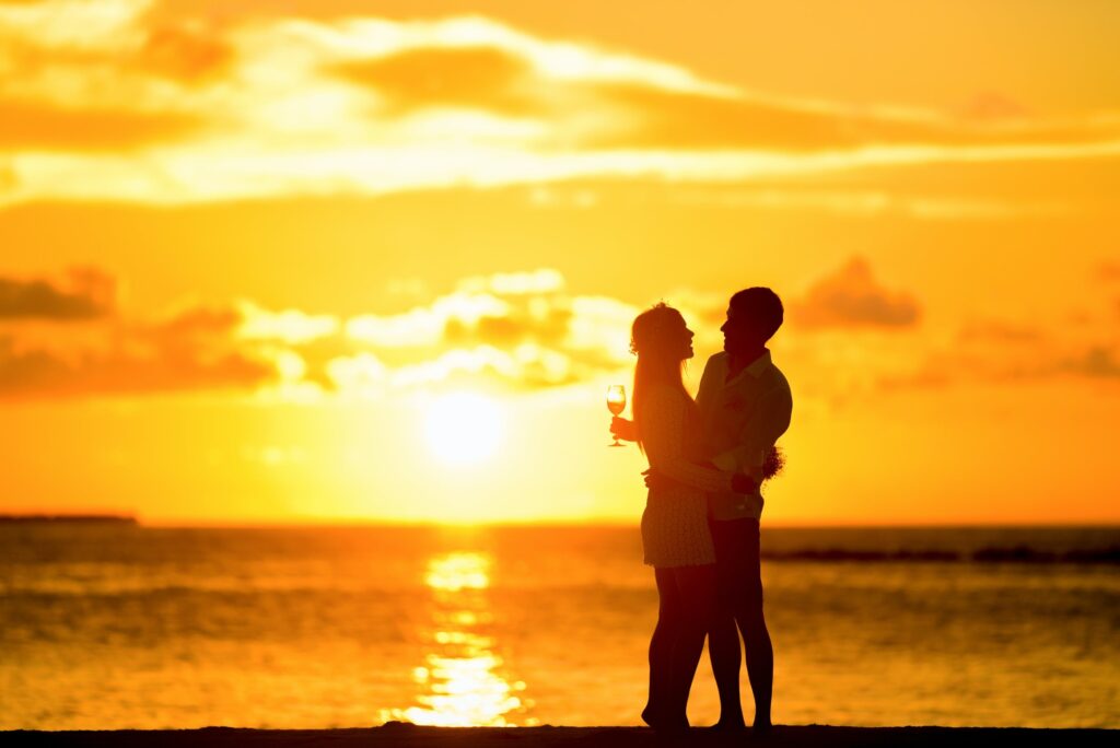 A couple embraces in front of a sunset
